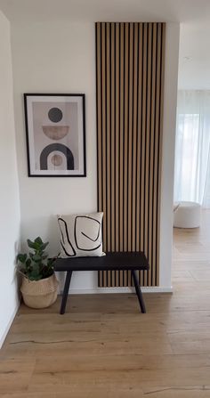 a bench in front of a wall with vertical stripes on it and a potted plant next to it