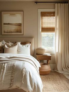 a bed sitting under a window next to a wooden table with a basket on top of it