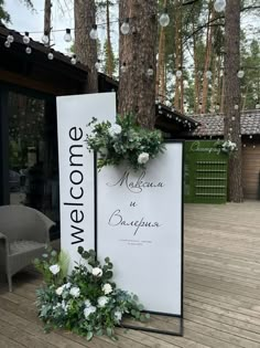 a welcome sign with flowers and greenery on it