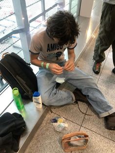 a young man sitting on the ground with his feet up and holding something in his hand