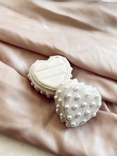 a heart - shaped brooch is laying on a pink satin sheet