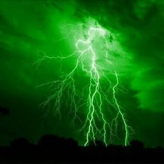 a green and black photo with lightning in the sky