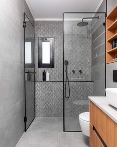 a bathroom with a walk in shower next to a white toilet and wooden cabinetry