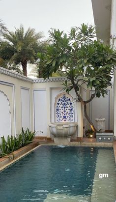 an outdoor swimming pool with a tree in the middle and tile work on the walls