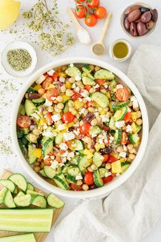 a bowl filled with cucumbers, tomatoes and other vegetables next to some seasonings