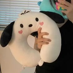 a woman taking a selfie with her cell phone while holding a stuffed animal pillow