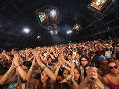 a large group of people at a concert with their hands up in the air,