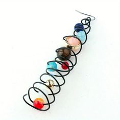 a set of seven rings with different colored glass beads on each one ring is attached to a black wire