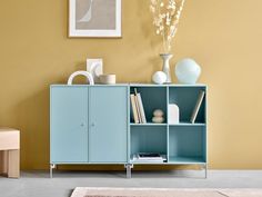 a blue cabinet sitting on top of a floor next to a vase and a chair