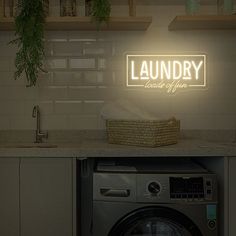 a washer and dryer sitting in a kitchen under a neon sign that reads laundry