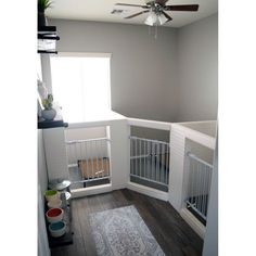 a room with white walls and wooden flooring has a ceiling fan in the corner