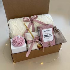 a gift box with soaps, candles and blankets in it on a white table