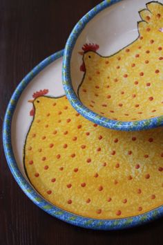 two yellow and blue plates with designs on them sitting on a wooden table next to each other