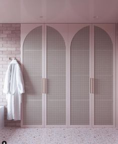 a white robe hanging on a wall next to a brick wall and two closets