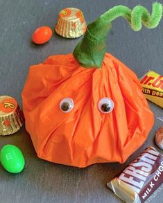 an orange bag with googly eyes and candy on the ground next to it is labeled easy pumpkin treat bags