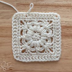 a crocheted square is shown on a wooden surface