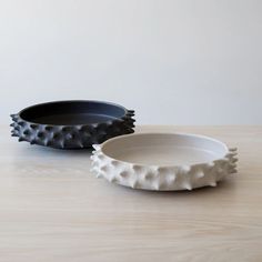 two black and white plates sitting on top of a wooden table next to each other