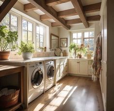 a washer and dryer in a room with wooden beams on the ceiling next to windows