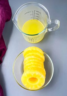 a glass measuring cup filled with yellow liquid next to a sliced pineapple