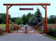 an old red gate with a sign hanging from it's side and trees in the background