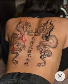 the back of a woman's body with chinese writing on it and two dragon tattoos