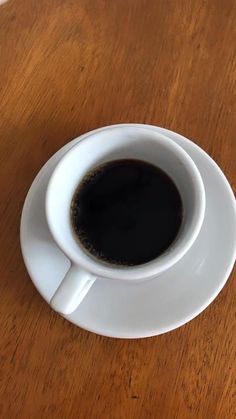 a cup of coffee sitting on top of a wooden table