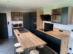 a modern kitchen with black and white brick walls, wooden counter tops and bar stools