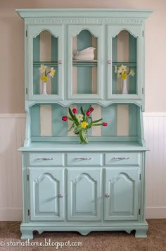 a blue china cabinet with flowers in it