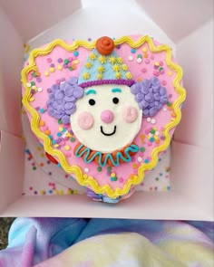 there is a cake in the shape of a clown's face on top of a box