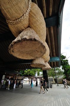 some people are walking around in an open area with large objects hanging from the ceiling