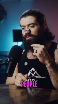 a man sitting at a table with a microphone in front of him and the words people written on his chest