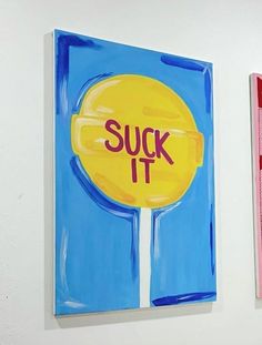 two paintings are hanging on the wall next to each other, one has a yellow lollipop