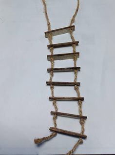 a ladder made out of sticks and rope on top of a white surface with a string attached to it