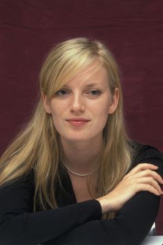 a woman sitting at a table with her arms crossed and looking off to the side