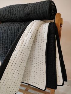 a black and white quilted blanket on a wooden rocking chair with it's back facing the camera