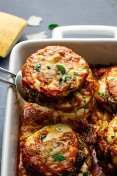 a white casserole dish filled with meat and cheese covered in marinara sauce