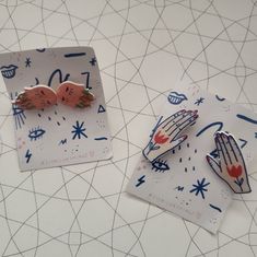 two pieces of paper with designs on them sitting next to each other, one has a hand and the other has a heart