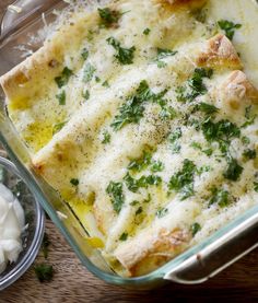 a casserole dish with cheese and parsley in it on a wooden table