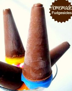 two chocolate cones sitting on top of each other in a glass bowl with the words homemade fudgesices written above them