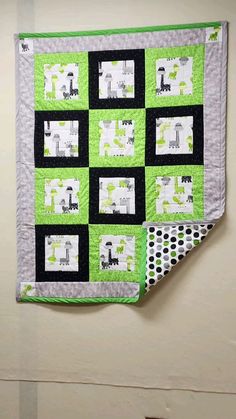 a green and white quilt hanging on the wall