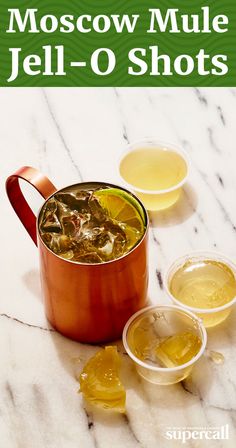 a red pot filled with liquid next to two cups and spoons on a marble surface