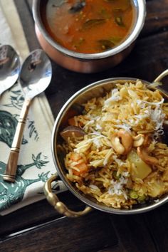 two bowls of food on a table with spoons next to it and a napkin