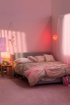 a bed with pink sheets and pillows in a bedroom