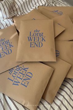 six brown bags with the words the long week end printed on them sitting on a bed