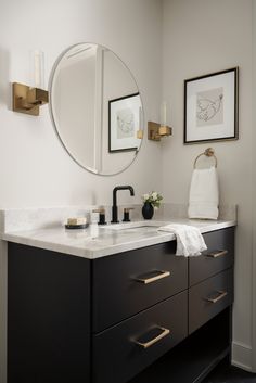 a bathroom with a sink, mirror and two pictures on the wall above it's counter