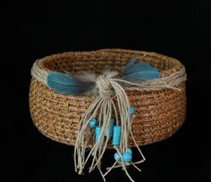 a woven basket with blue beads and feathers in it on a black tablecloth background