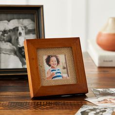 a wooden frame sitting on top of a table next to two pictures and a cup