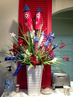 a vase filled with red, white and blue flowers sitting on top of a counter