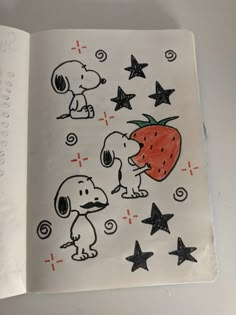 an open book with drawings of dogs and strawberries on the pages, including stars