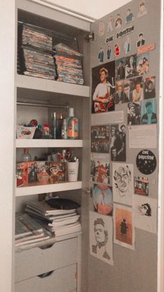 an open refrigerator with various items on the shelves and pictures on the wall behind it